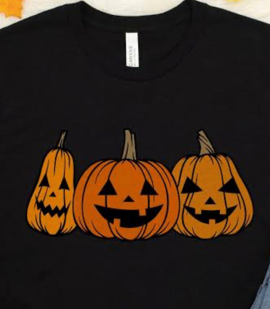 Black t-shirt with three jack-o'-lanterns printed on it.